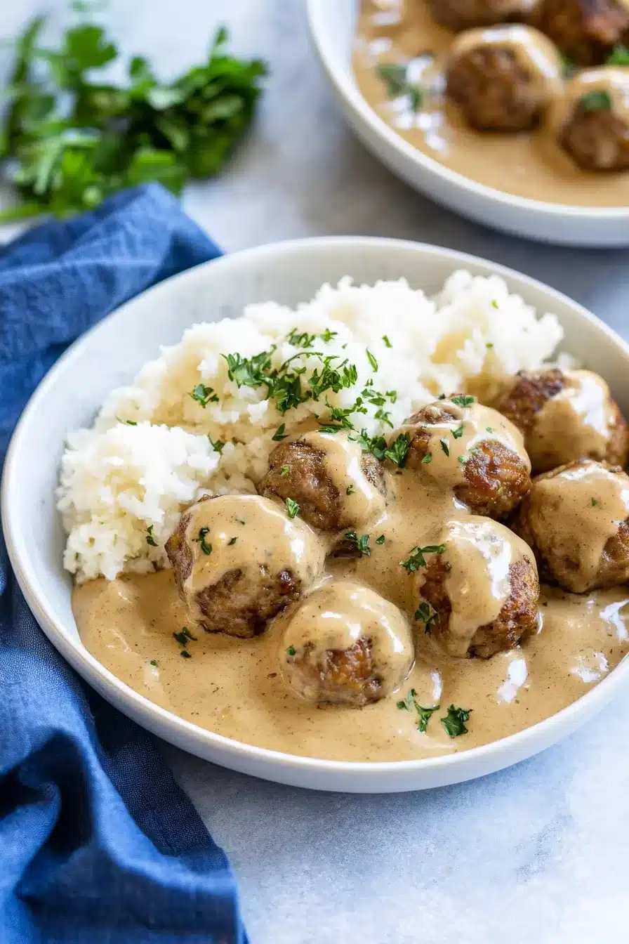 Steamy bowl of fluffy jasmine rice topped with Swedish meatballs and rich gravy pooling over the grains