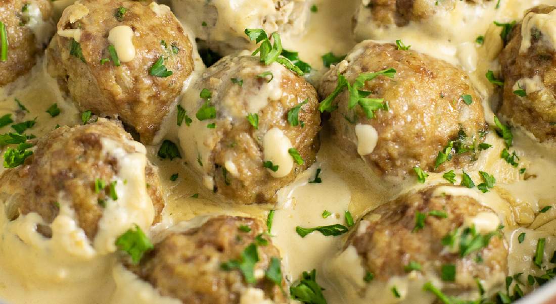 Swedish meatballs in golden mustard-flecked cream sauce garnished with chopped flat-leaf parsley