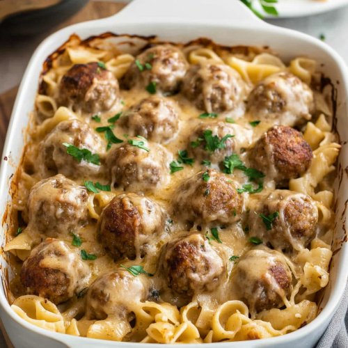 Baking dish of bubbly Swedish meatballs, egg noodles, and golden melted cheese fresh out of the oven