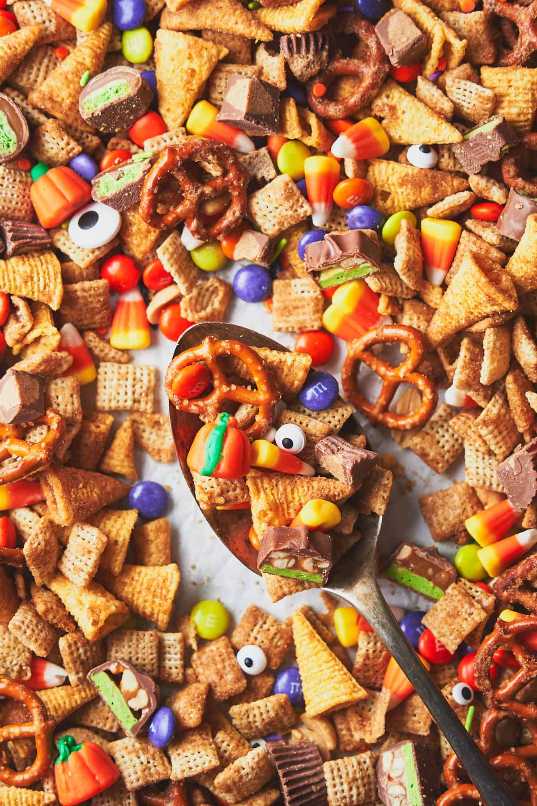 Bowl of mixed pretzels, candy corn, chocolate-covered raisins, and orange cheese crackers