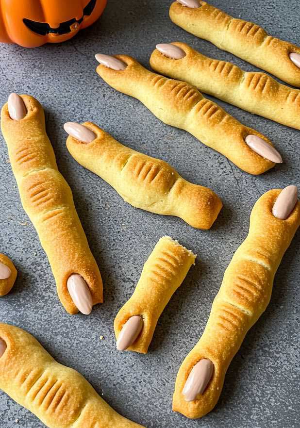Golden baked breadsticks shaped like fingers with almond nail tips and olive pits