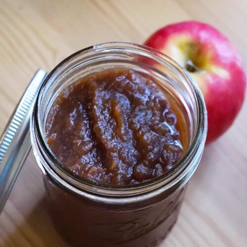 Spiced apple butter in a mason jar, golden hue, aromatic cinnamon and cloves, ideal for autumn spreads