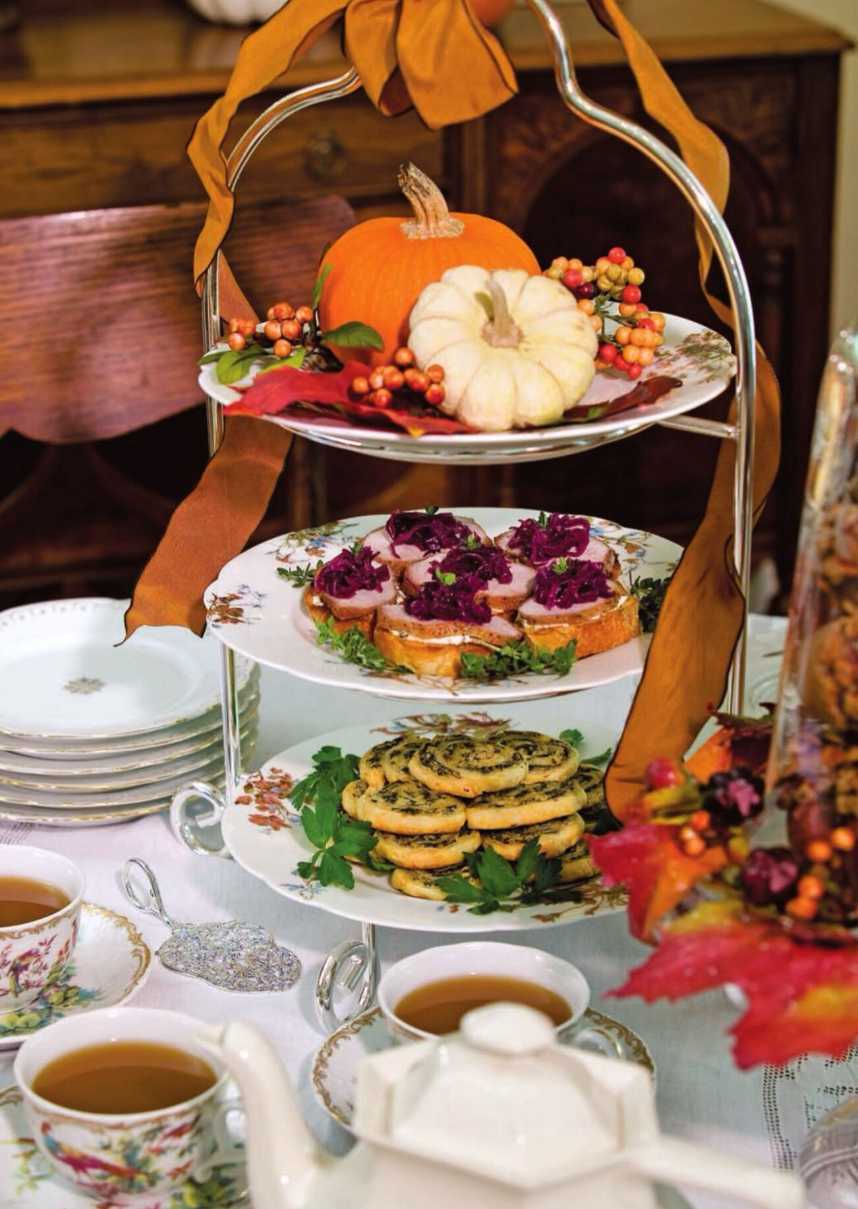 Three-tier stand filled with savory fall bites, mini quiches, and herb crusts on a rustic table