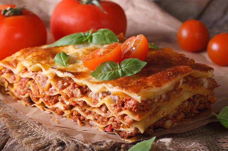 Hearty bolognese lasagna with beef, parmesan, basil, rich tomato sauce, layered pasta.