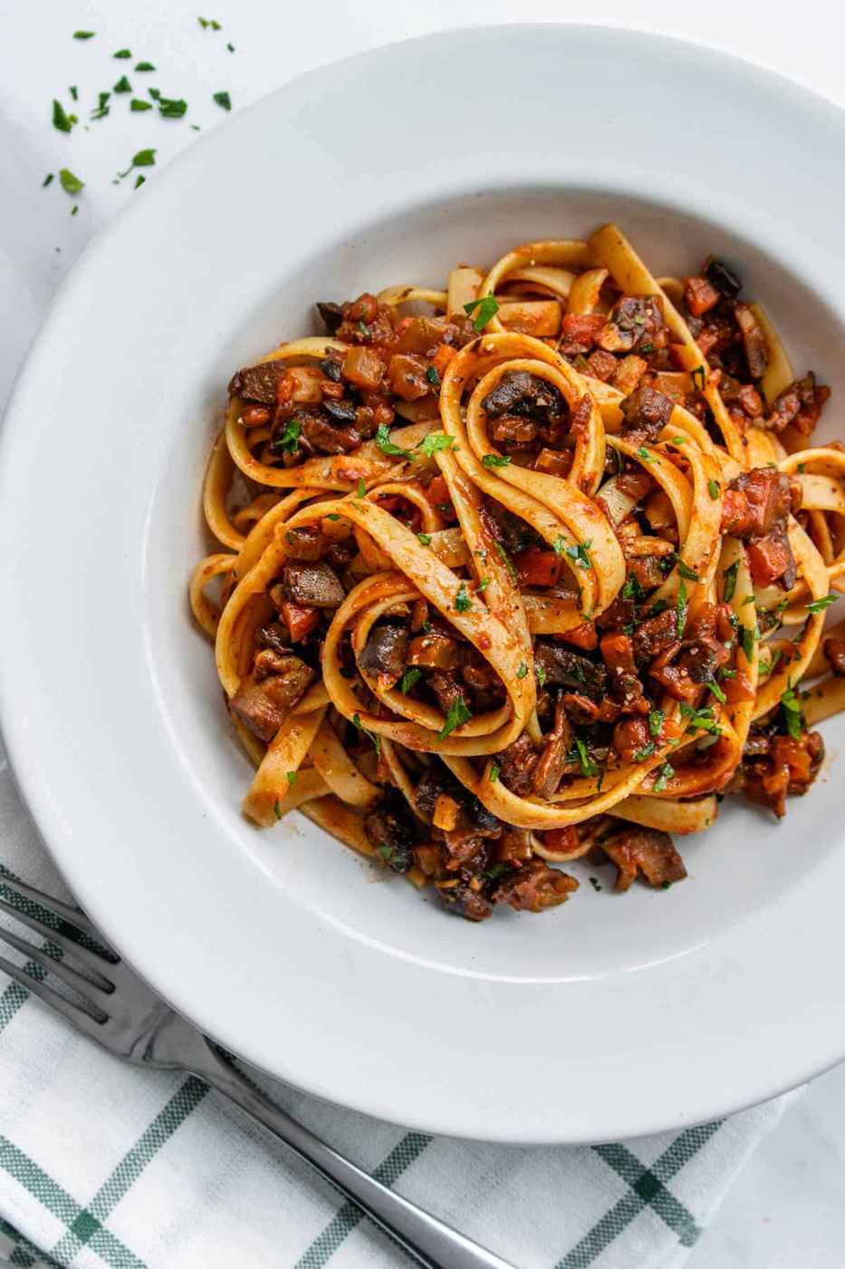 Vegan bolognese sauce simmering in a rustic pot, rich tomato base with plant-based protein.