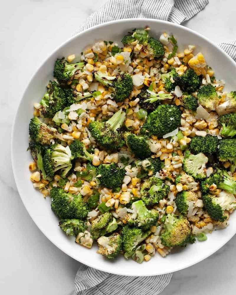 Grilled broccoli salad drizzled with balsamic glaze, toasted pecans, and shaved Manchego cheese