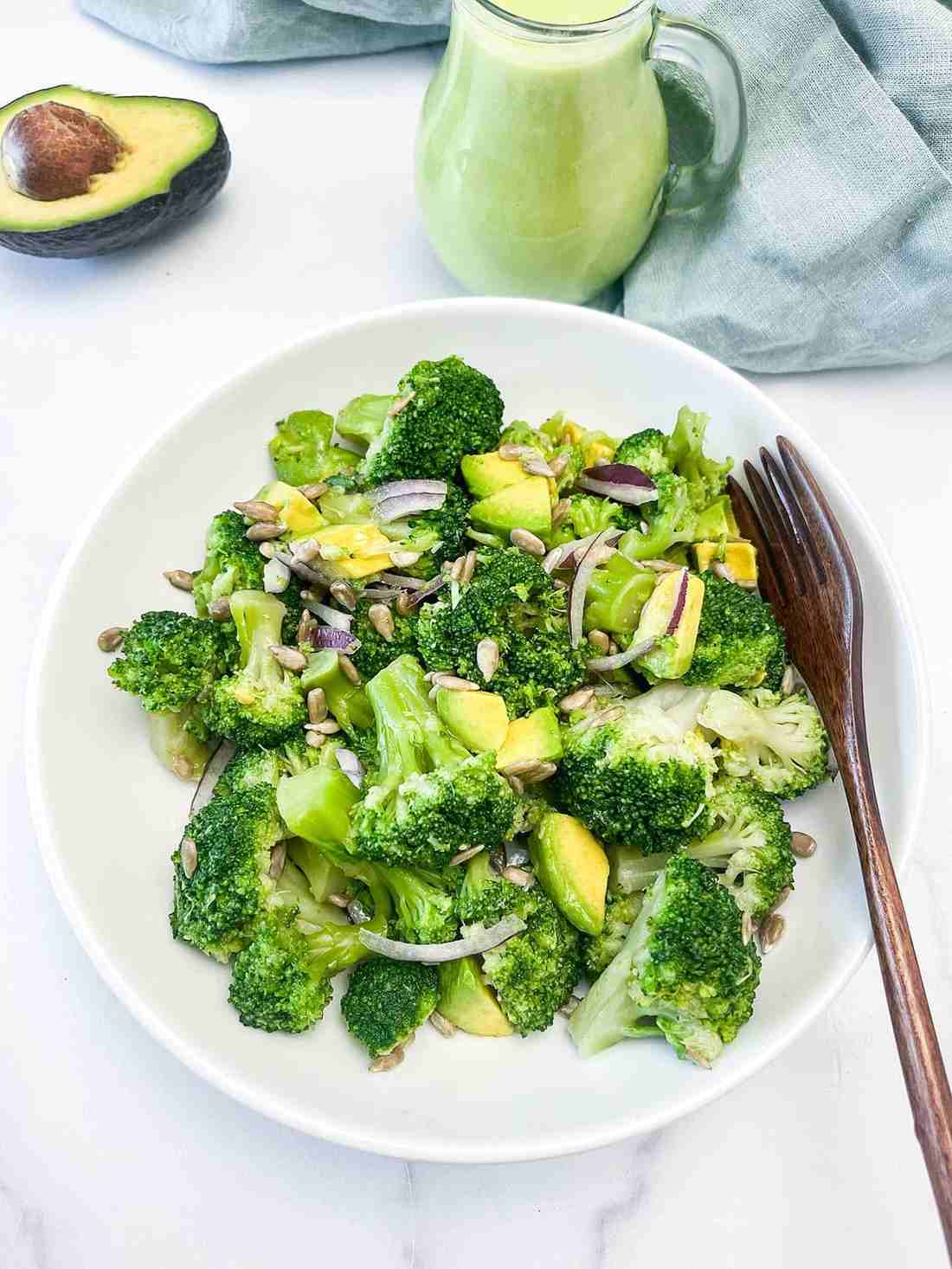 Vegan broccoli salad with florets, creamy tahini‑lime dressing, pumpkin seeds, dried apricots, and vegan cheese crumbles