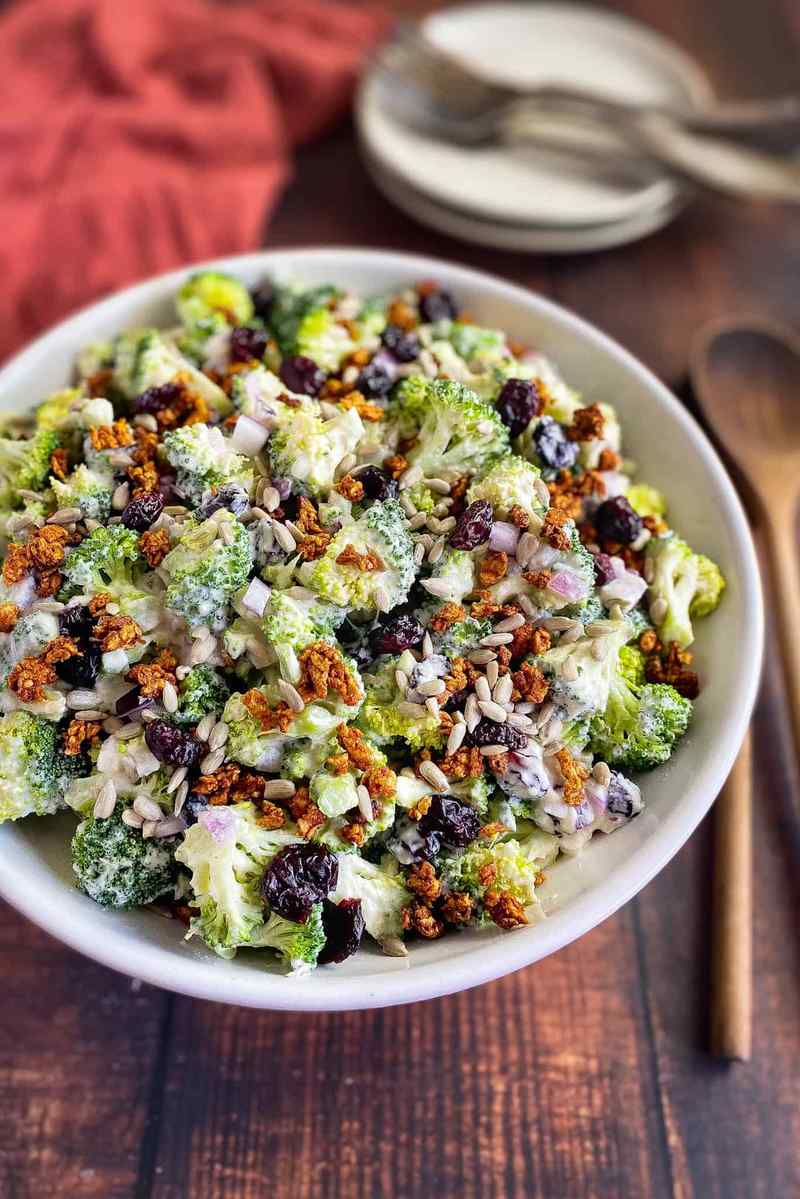 Vegan broccoli salad with florets, miso‑ginger dressing, sesame seeds, dried mango, and vegan feta crumble