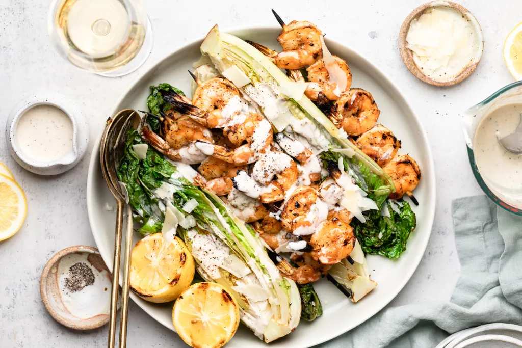 Grilled shrimp caesar salad with succulent herb shrimp crisp romaine lettuce and parmesan ribbons