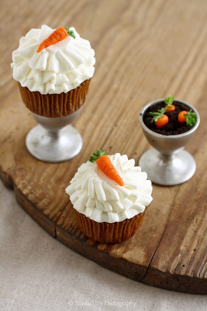 Carrot cupcake crowned with chopped walnuts and pecans, moist spiced crumb, and creamy frosting
