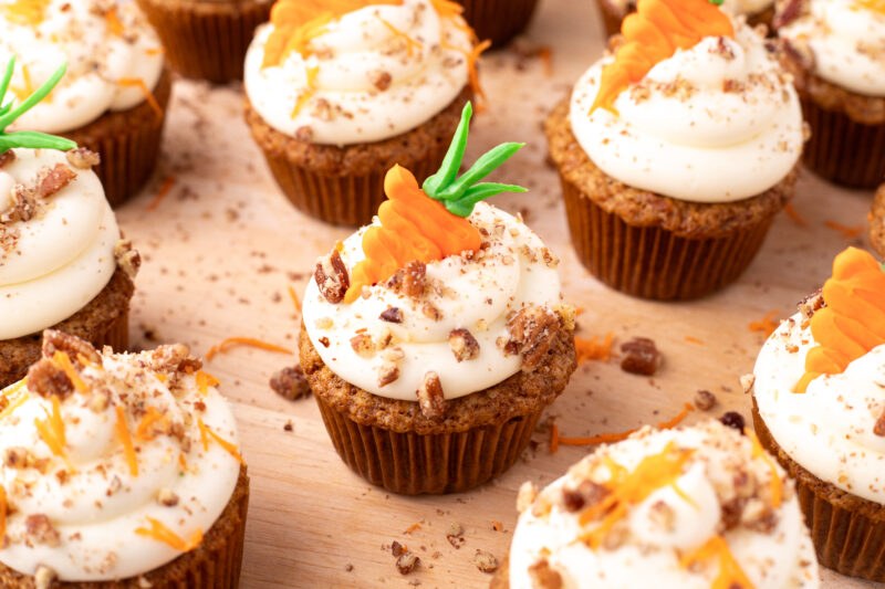 Classic carrot cake cupcakes topped with thick cream cheese frosting and a sprinkle of walnuts