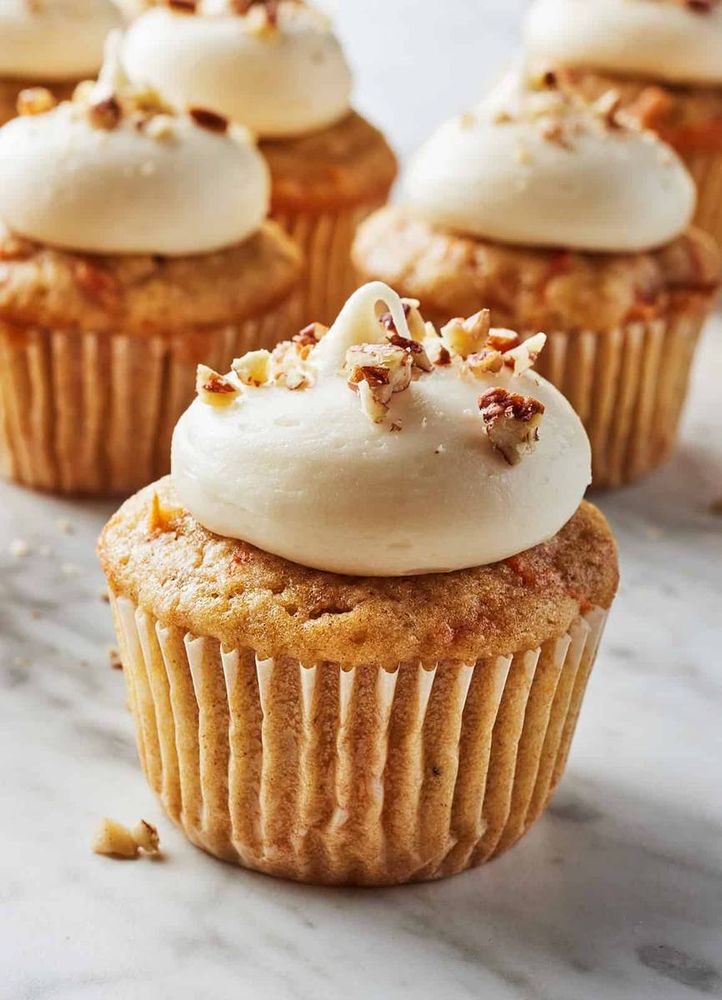 Classic carrot cupcake swirled with tangy cream cheese frosting, moist spiced crumb, and toasted walnuts