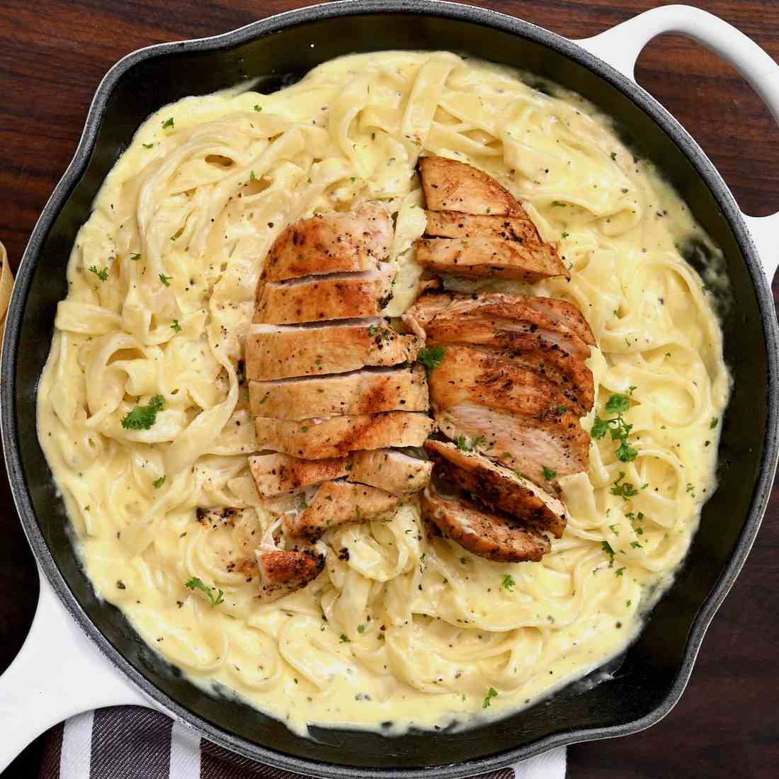 Golden fettuccine tossed in silky parmesan cream sauce with tender chicken strips, steam rising