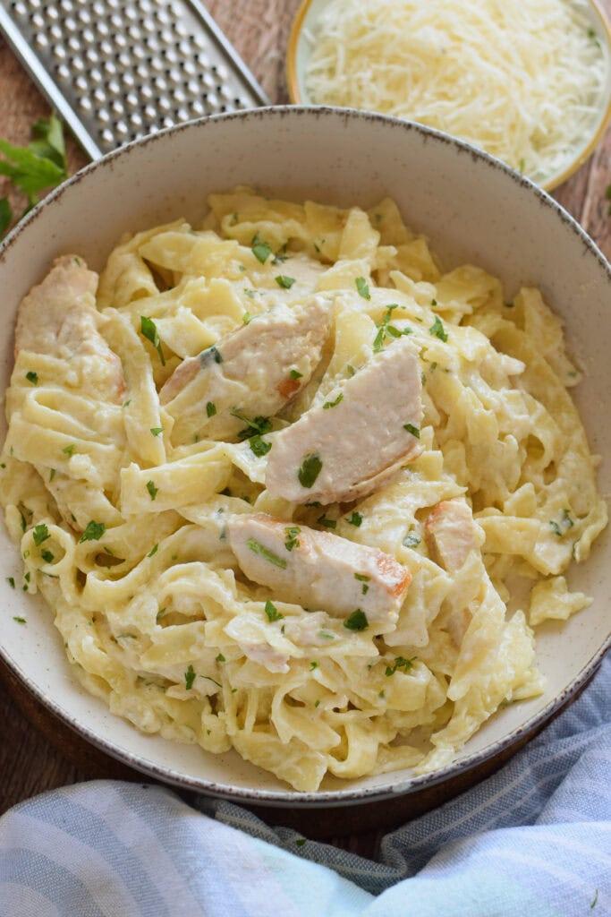 Golden chicken strips atop silky parmesan cream sauce, twirled with al dente fettuccine, steam rising.