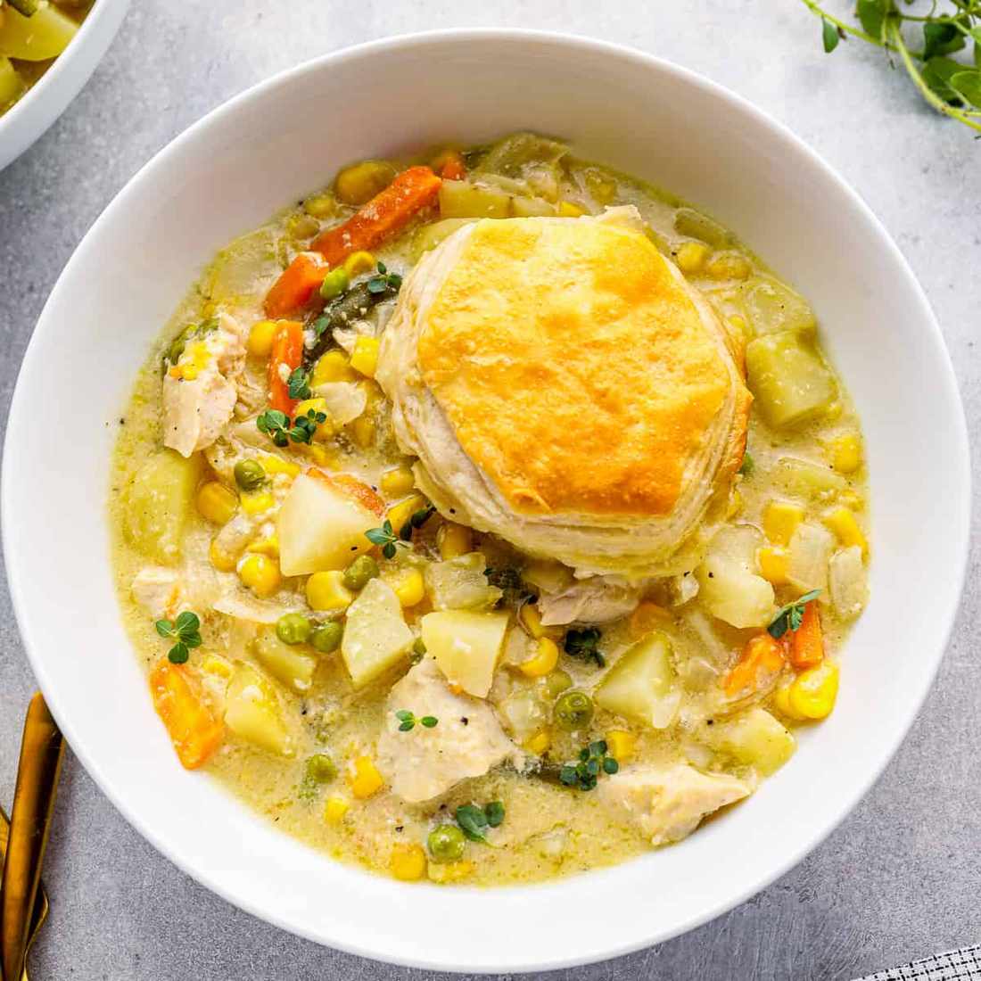 Creamy chicken pot pie soup with tender chicken, peas, carrots, potatoes, and flaky biscuit topping