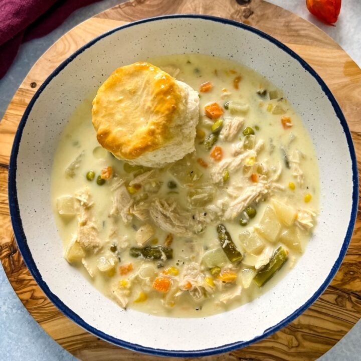 Creamy chicken pot pie soup with chicken, peas, carrots, potatoes, and buttery puff pastry topping