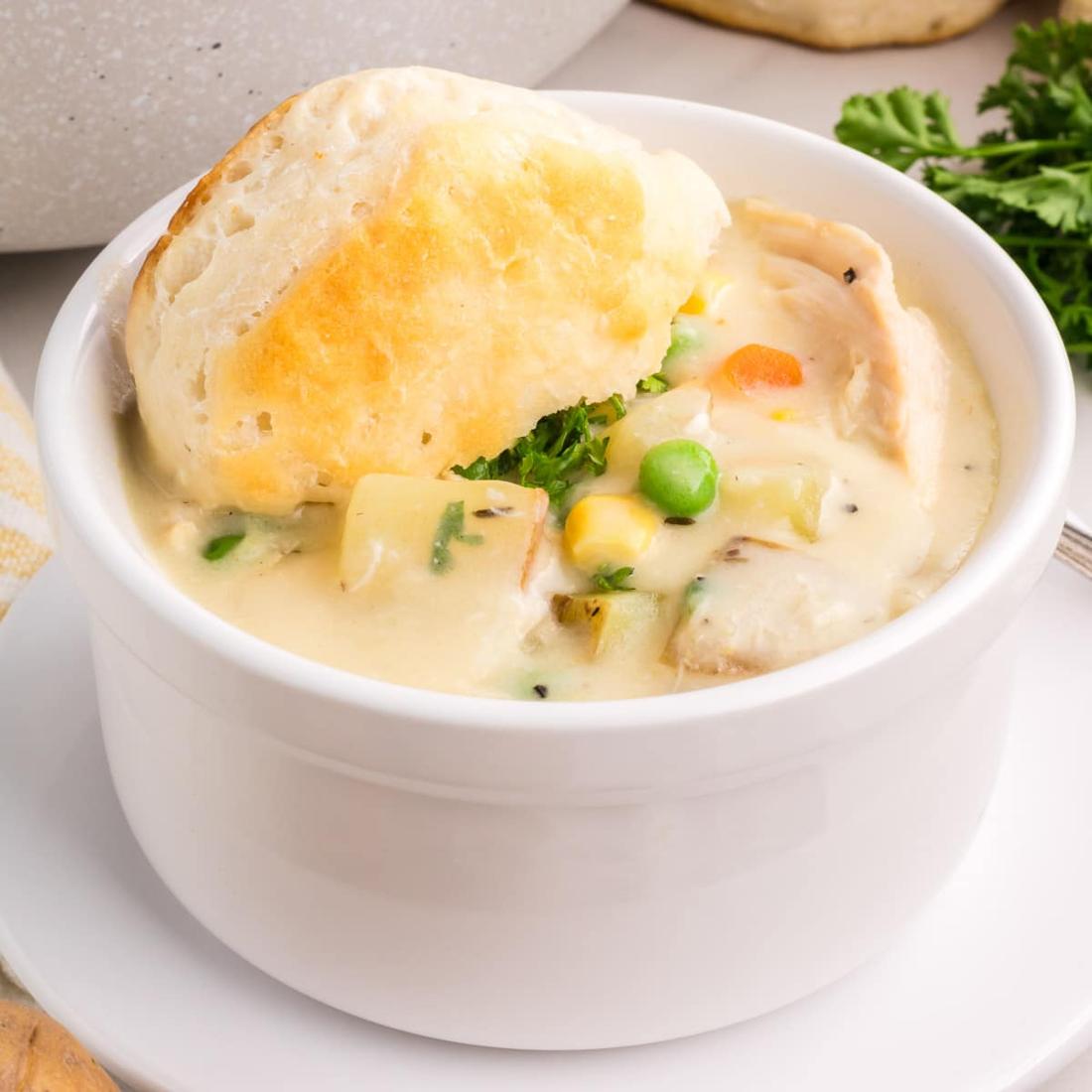 Creamy chicken pot pie soup with chicken, peas, carrots, potatoes, and garlic‑butter pastry topping