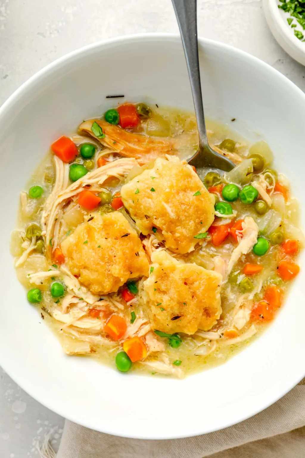 Slow cooker chicken pot pie soup with creamy broth, tender chicken, peas, carrots, potatoes, and buttery biscuit topping