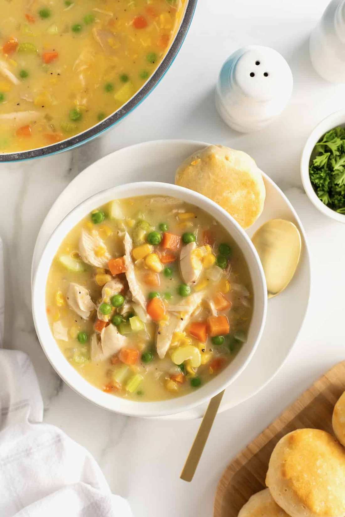 Creamy chicken pot pie soup with tender chicken, peas, carrots, potatoes, and buttery biscuit topping