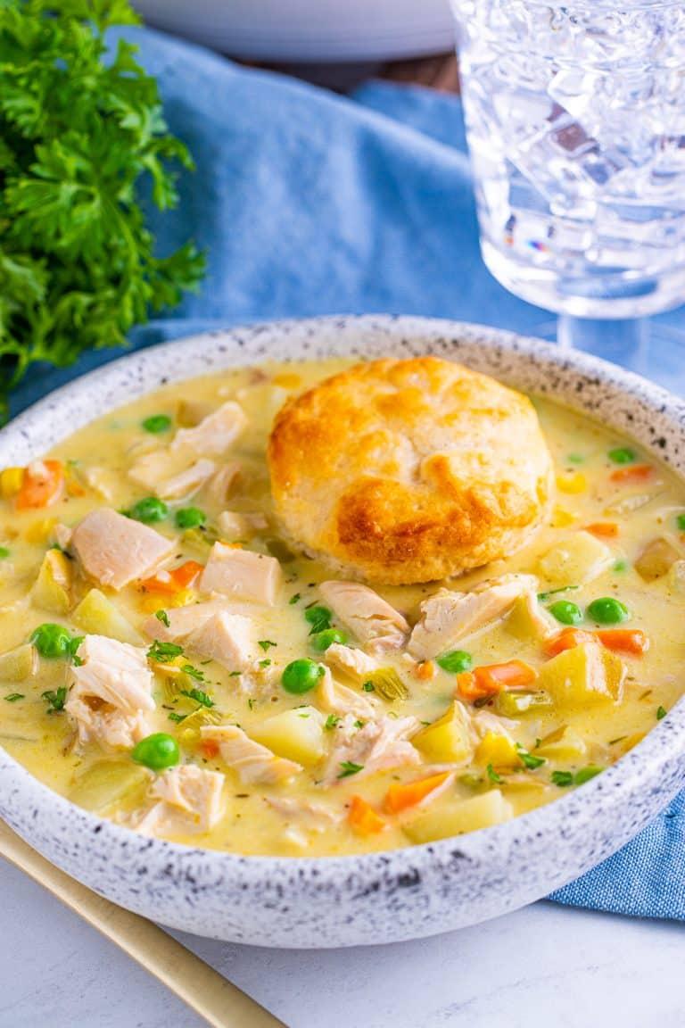 Creamy chicken pot pie soup topped with herb‑butter biscuit crumbles, peas, carrots, potatoes