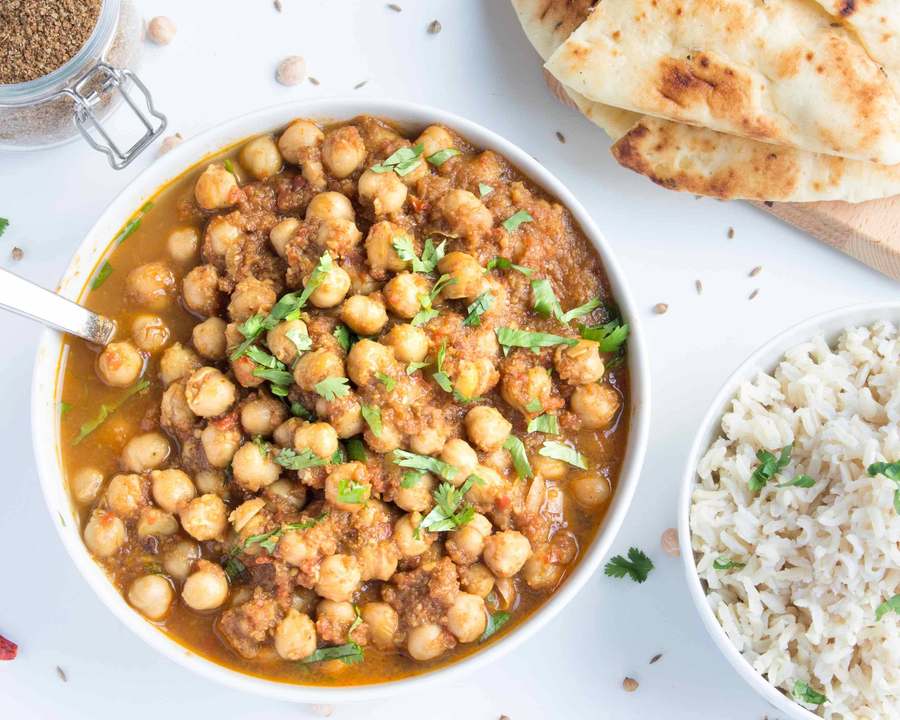 Creamy chickpea curry with yogurt, spices, and a drizzle of cream, served with naan
