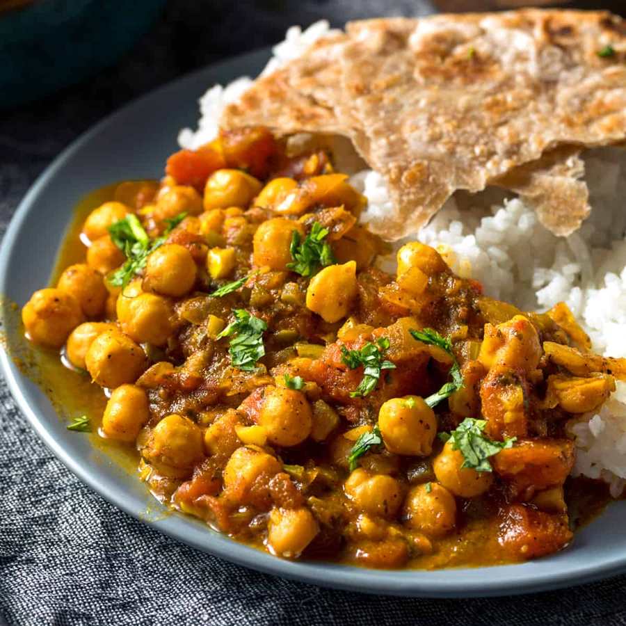 Roasted garlic classic chana masala with chickpeas, rich spicy curry sauce, cilantro, and flatbread naan.