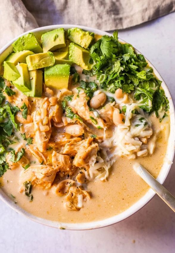 Chipotle spiced white chicken chili bowl garnished with green onions and avocado