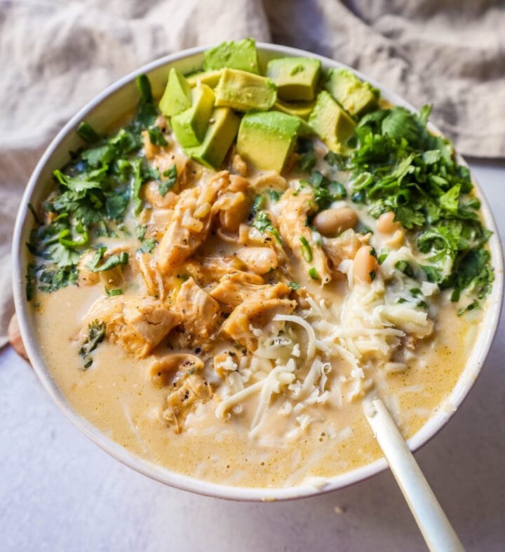 Cheesy green chile white chicken chili topped with bubbling melted cheese and sour cream