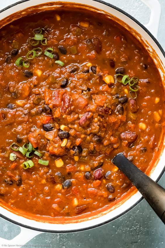Quinoa and black bean vegetarian chili served in a ceramic bowl with sliced avocado