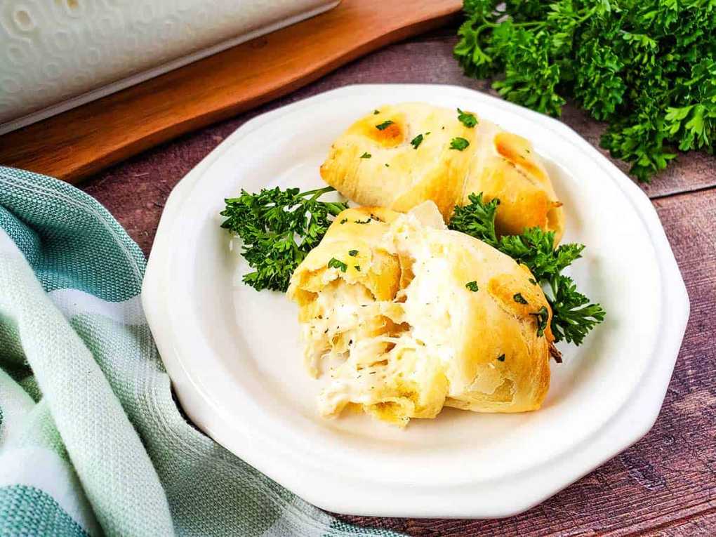 Golden crescent roll pockets filled with creamy chicken, herbs, and melted cheese on a holiday platter