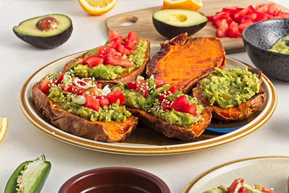 Roasted sweet potato halves filled with vibrant green guacamole, topped with pico de gallo