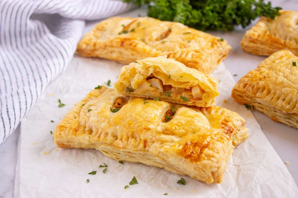 Golden puff pastry hand pies filled with savory chicken, peas, and herbs, served on a festive platter