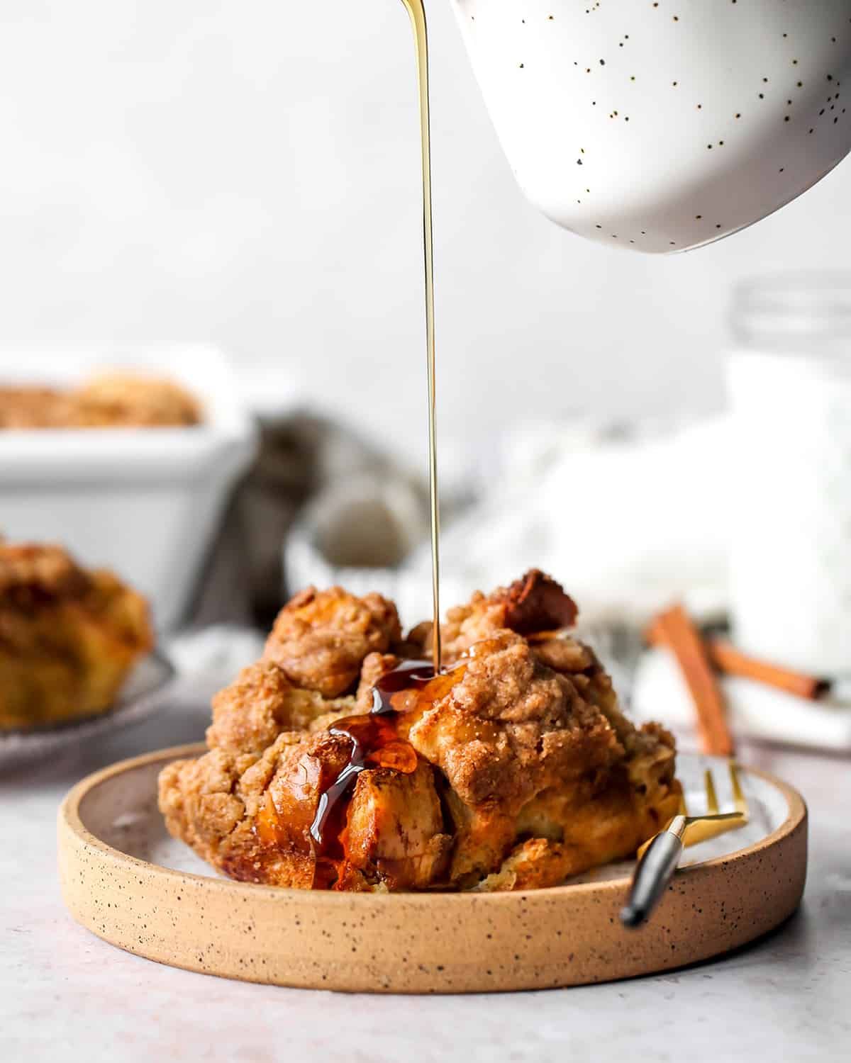 Baked French toast casserole topped with caramelized cinnamon roll pieces and maple syrup