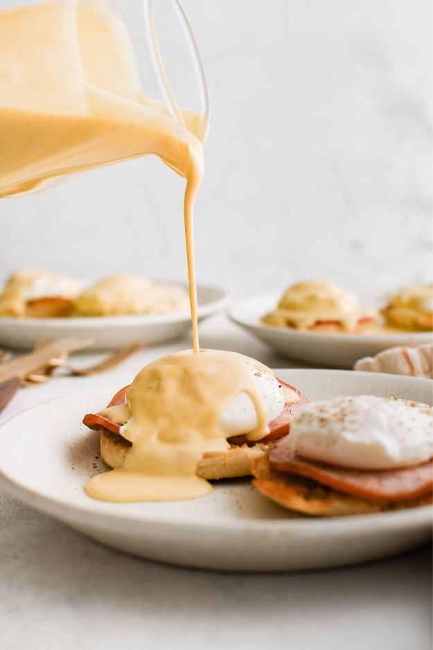 Poached eggs atop English muffins and ham, smothered in golden hollandaise sauce