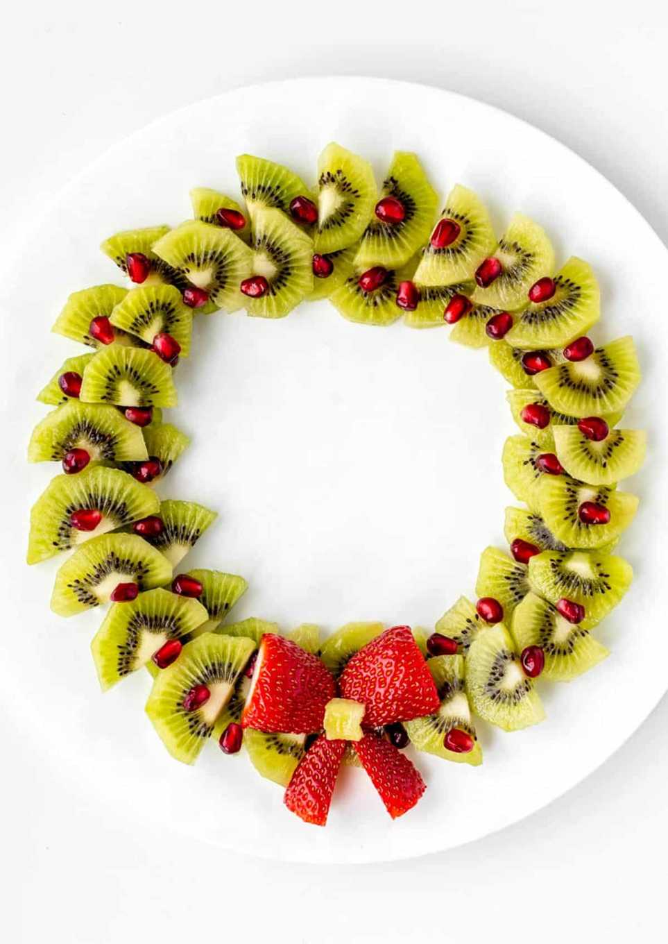 Vibrant fruit wreath of kiwi slices and pomegranate seeds with a strawberry centerpiece