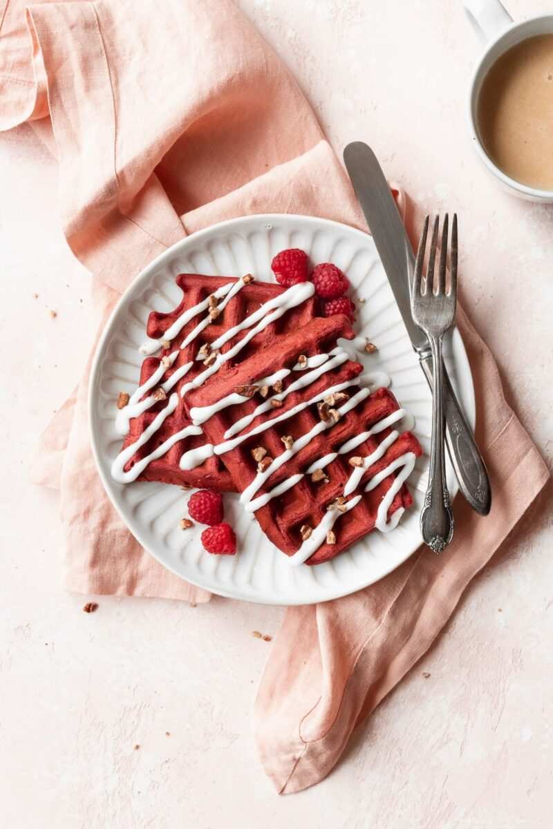 Crimson waffles topped with a glossy cream cheese drizzle and fresh berries