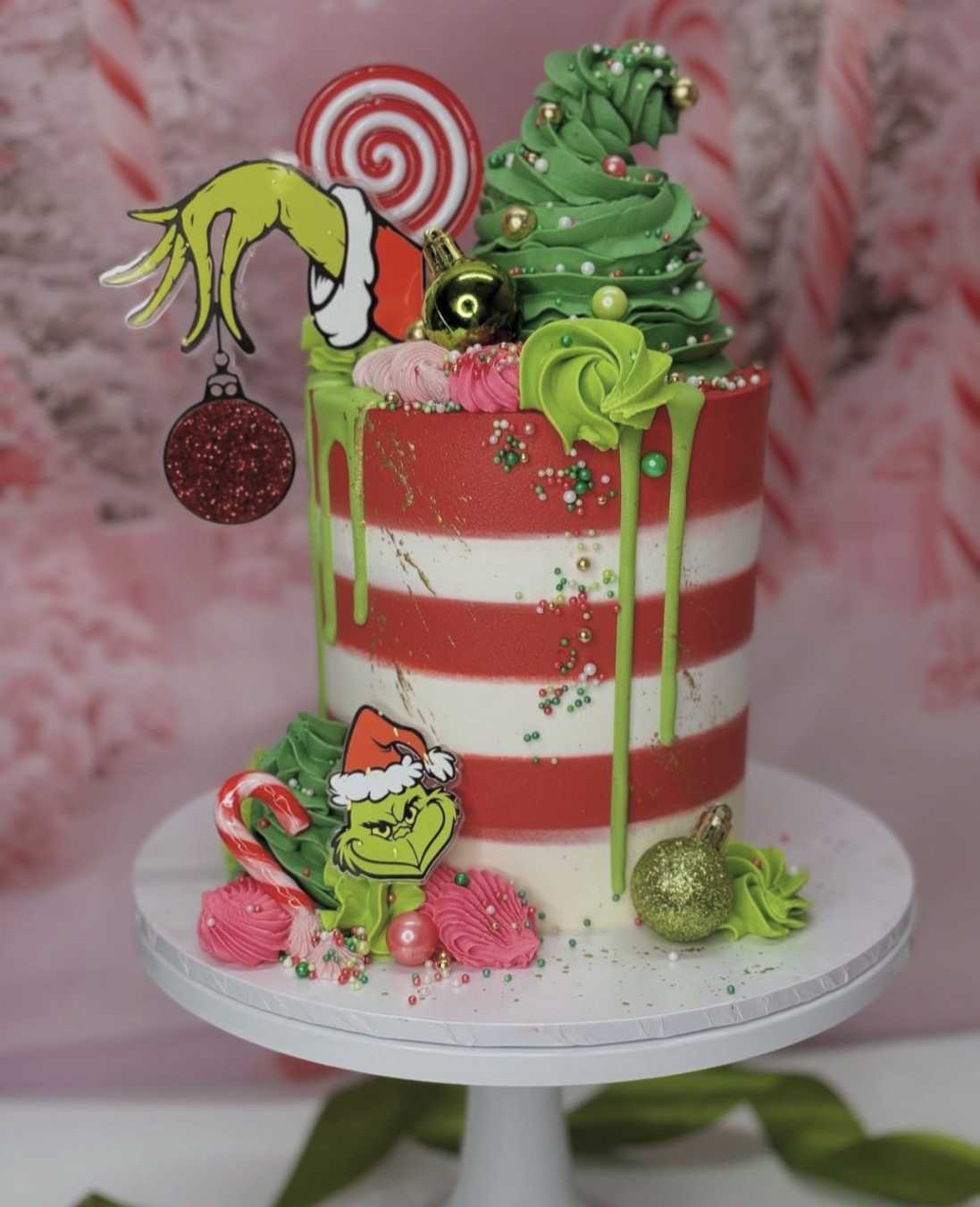 Dark chocolate cake with red‑green candy cane stripes and glossy white chocolate drip