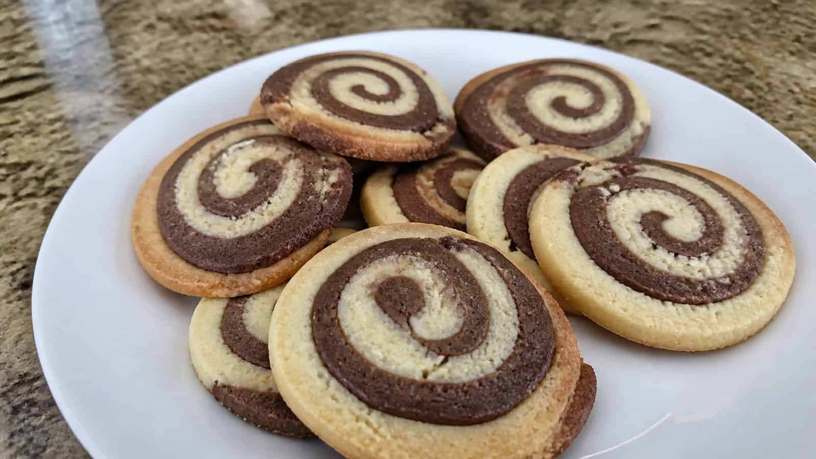 Swirled chocolate and vanilla shortbread cookies sliced into pinwheels on a white plate.