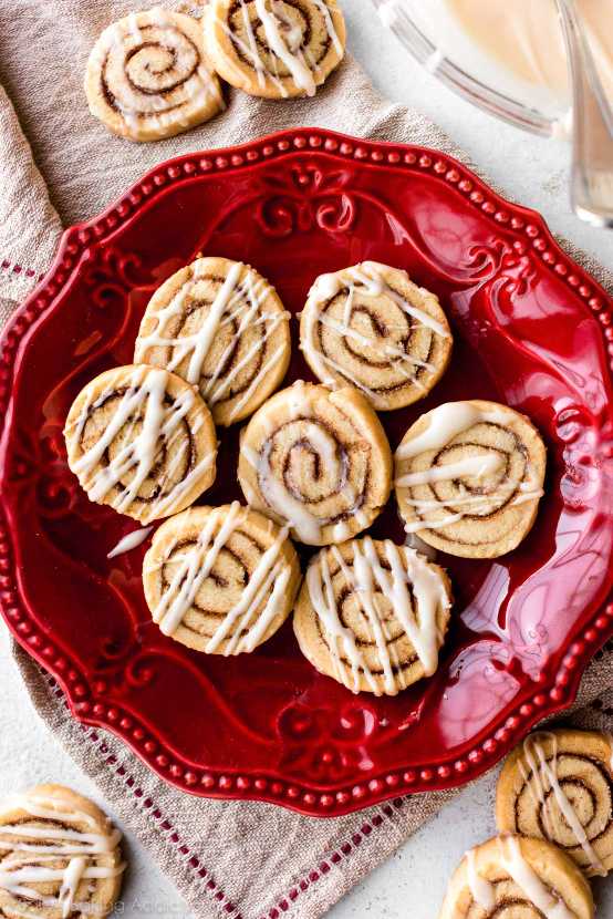 Sugar cookies with a visible cinnamon sugar swirl inside, glazed with white icing on a plate.
