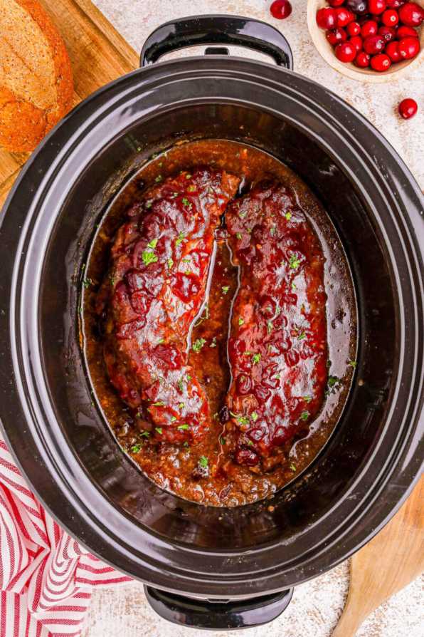 Tender pork tenderloin glazed with a shiny cranberry sauce, garnished with rosemary sprigs