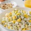 Creamy potato egg salad sprinkled with paprika, chives, and crispy bacon bits