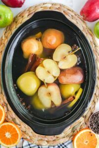 Warm apple cider simmering with cinnamon sticks, star anise, and orange slices