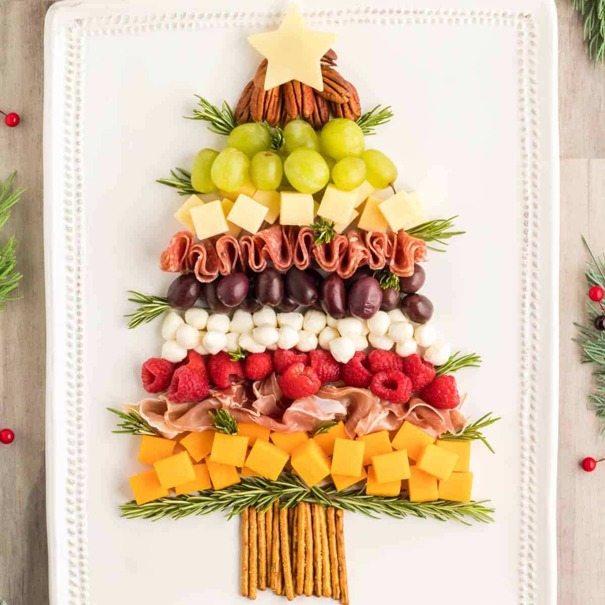 Festive charcuterie board shaped like a Christmas tree with meats, cheeses, and berries