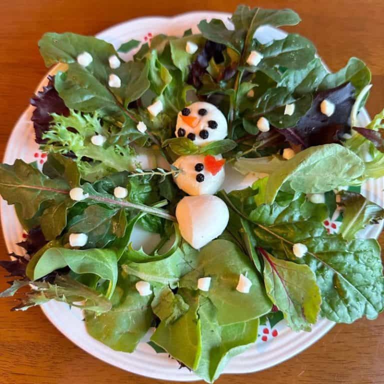 Snowman-shaped mozzarella salad with cherry tomatoes, olives, and basil