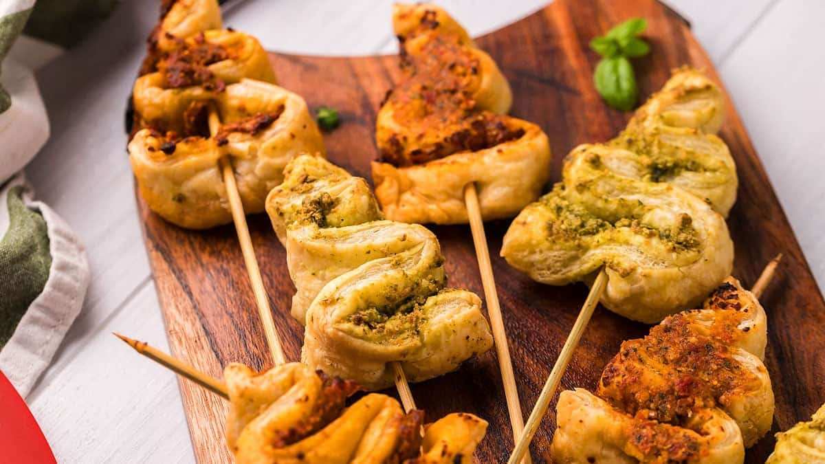 Green pesto‑coated pastry strips arranged like tiny Christmas trees on skewers