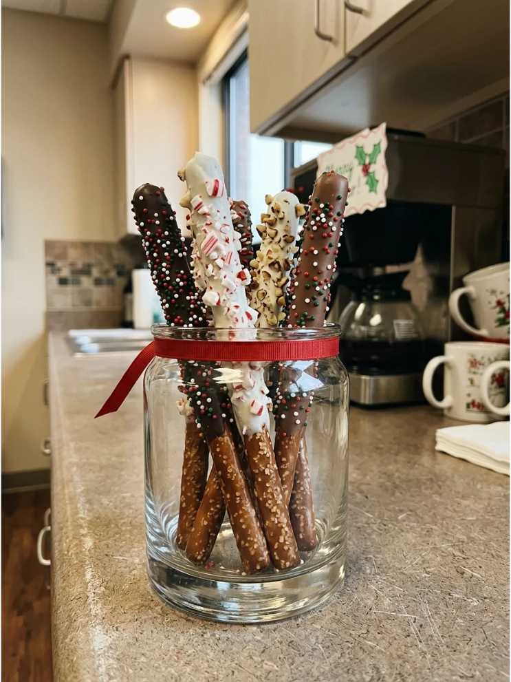 Crunchy pretzel rods coated in dark chocolate and colorful sprinkles, displayed on a festive platter