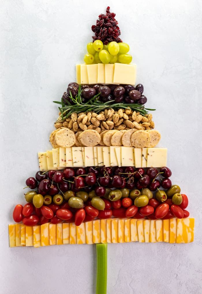 Green apple slices, cheese wedges, and nuts arranged into a festive tree shape on a platter