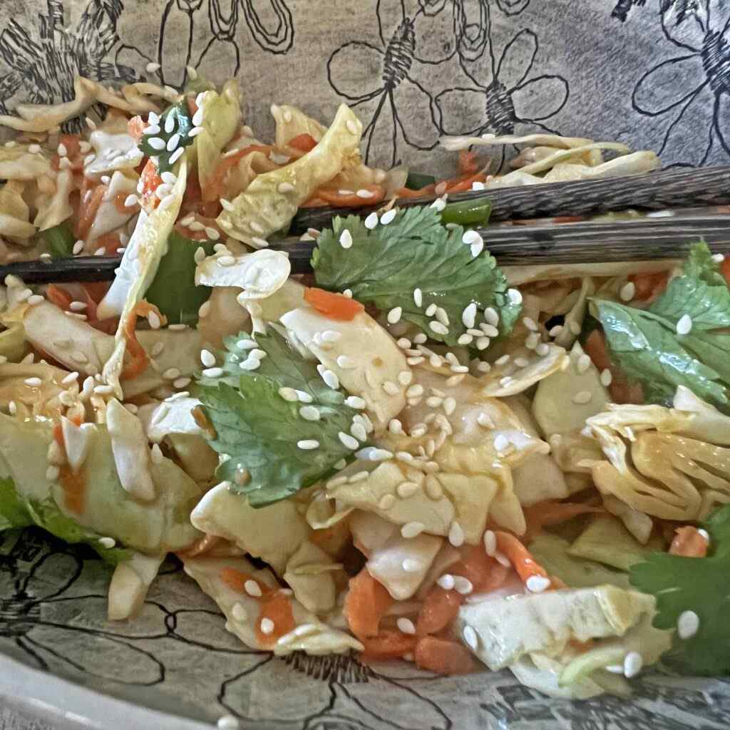 Vibrant Asian slaw with crisp cabbage, shredded carrots, and silky sesame dressing, garnished with toasted sesame seeds