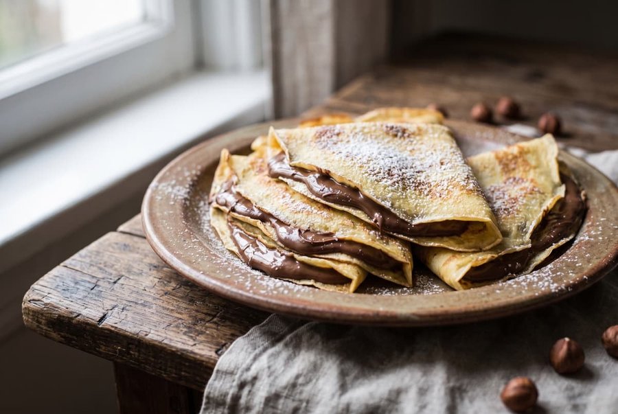 Light crepes filled with Nutella, drizzled with melted chocolate and topped with toasted hazelnuts