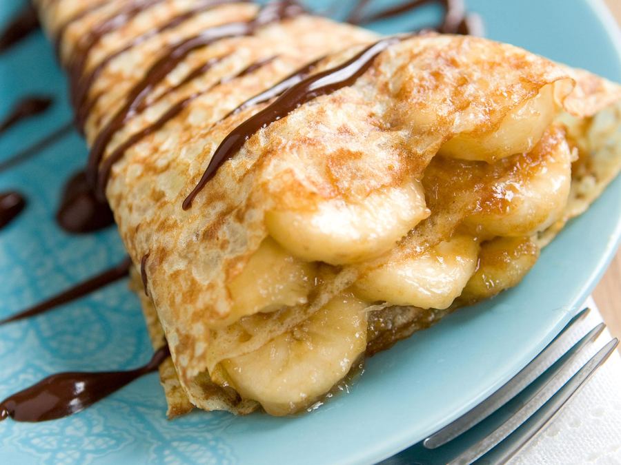 Golden crepes filled with strawberries and blueberries, topped with a citrus glaze and fresh mint